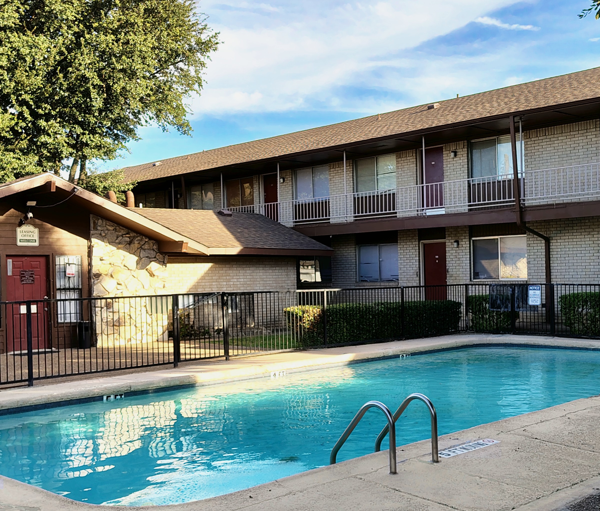 Edificio Parkaire de dos pisos con balcones y una piscina bajo un cielo azul