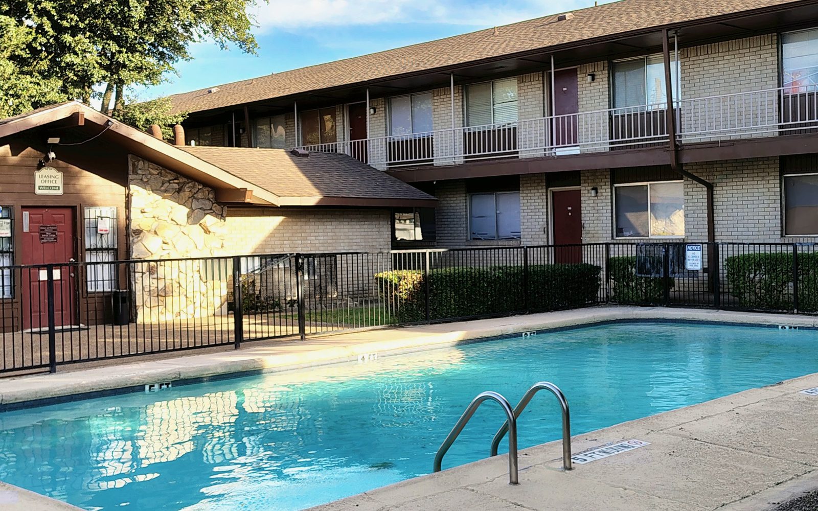 Piscina al aire libre junto al edificio Parkaire de dos pisos y la oficina de arrendamiento